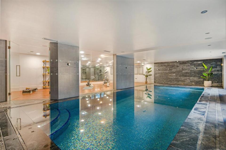 Indoor swimming pool with an adjacent gym visible through glass walls. qhxidiqxkiqxqinv